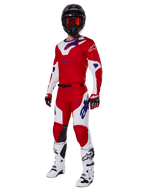 Zestaw Alpinestars 2025 Racer Veil, strój motocrossowy, jaskrawoczerwony i biały z niebieskimi akcentami logo, czarny kask, czerwone rękawice i białe buty, pełny zestaw ochronny do jazdy terenowej