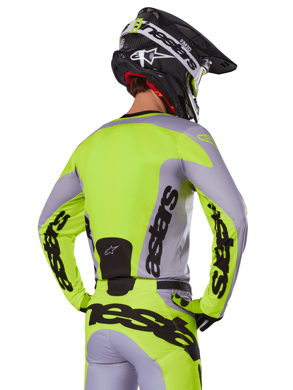 Zawodnik motocrossowy od tyłu w koszulce Alpinestars 2025 Racer Veil w kolorze szarym i neonowym żółtym, z wyraźnym logo „astars” na plecach i rękawach, w zestawie z dopasowanymi spodniami i czarnym kaskiem, kompletny strój wyścigowy