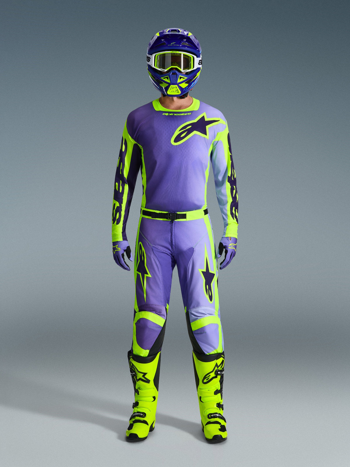 Koszulka Alpinestars 2026 Racer Portl, fioletowa i żółta fluo, noszona jako część kompletnego zestawu motocrossowego z pasującymi spodniami, kaskiem i jaskrawymi neonowożółtymi butami, profesjonalny strój do wyścigów off-road.