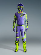Koszulka Alpinestars 2026 Racer Portl, fioletowa i żółta fluo, noszona jako część kompletnego zestawu motocrossowego z pasującymi spodniami, kaskiem i jaskrawymi neonowożółtymi butami, profesjonalny strój do wyścigów off-road.