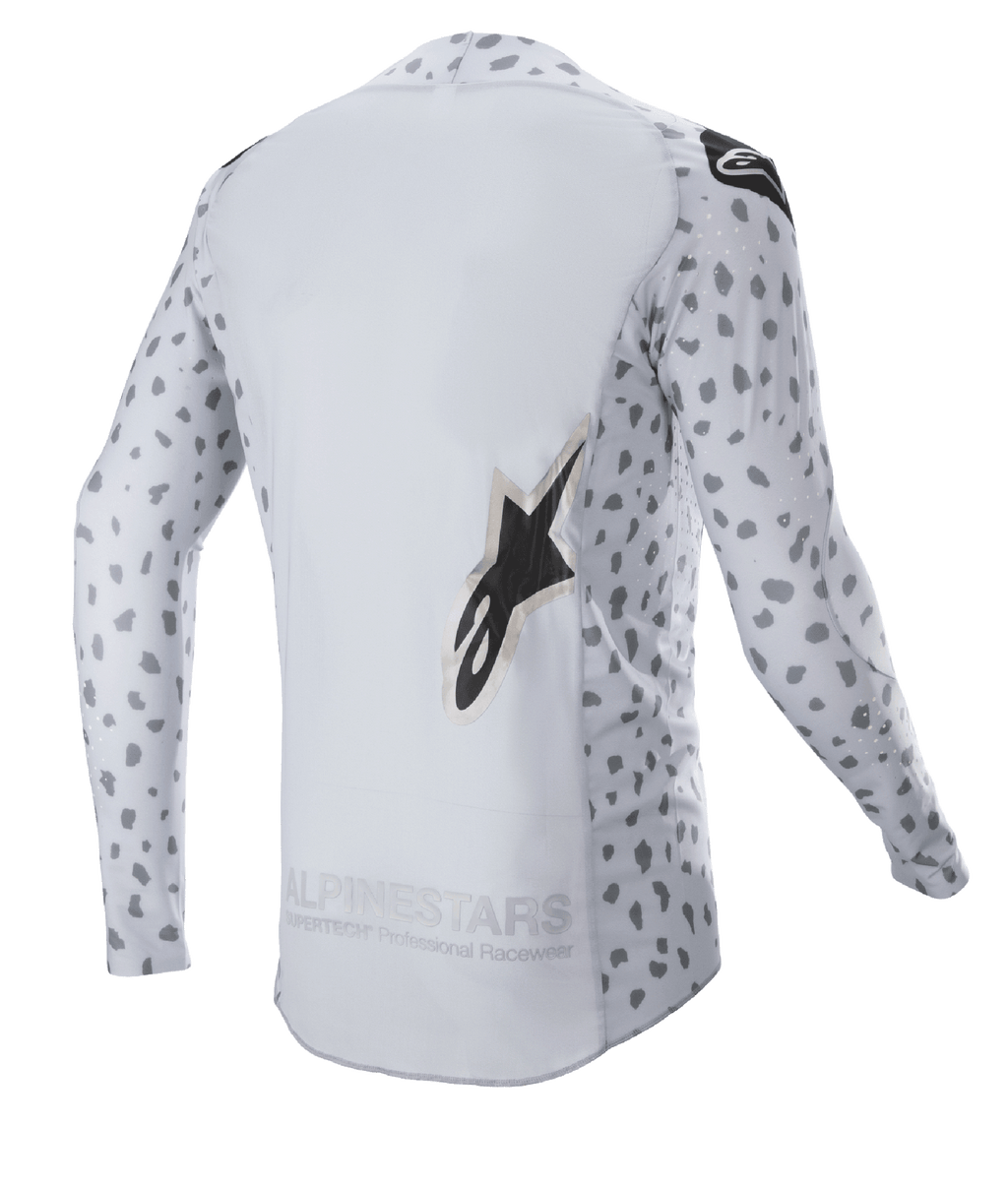 Alpinestars 2023 Supertech North Jersey, koszulka motocrossowa, kolor Haze Gray i czarny, widok z tyłu z abstrakcyjnym nakrapianym wzorem na rękawach i bokach, duże logo z gwiazdą, przedłużony tylny panel i oddychająca konstrukcja techniczna