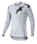 Alpinestars Supertech North Jersey 2023, koszulka motocrossowa, kolor Haze Gray i czarny, biała koszulka z długim rękawem z szarym nakrapianym wzorem na rękawach i bokach, czarne logo z gwiazdą na piersi i ramionach, elastyczna siateczka z zaokrąglonym dołem