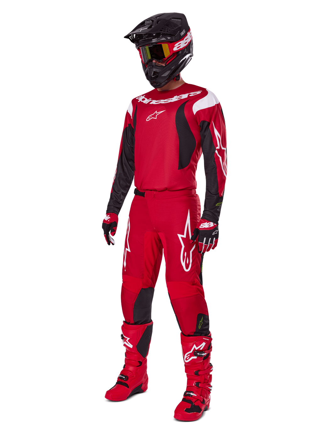 Zawodnik motocrossowy ubrany w zestaw Alpinestars Fluid Haul 2025, jasnoczerwony z czarnymi i białymi akcentami, kompletny strój zawierający koszulkę, spodnie, kask, buty i rękawice, zaprojektowany dla wydajności i ochrony off-road