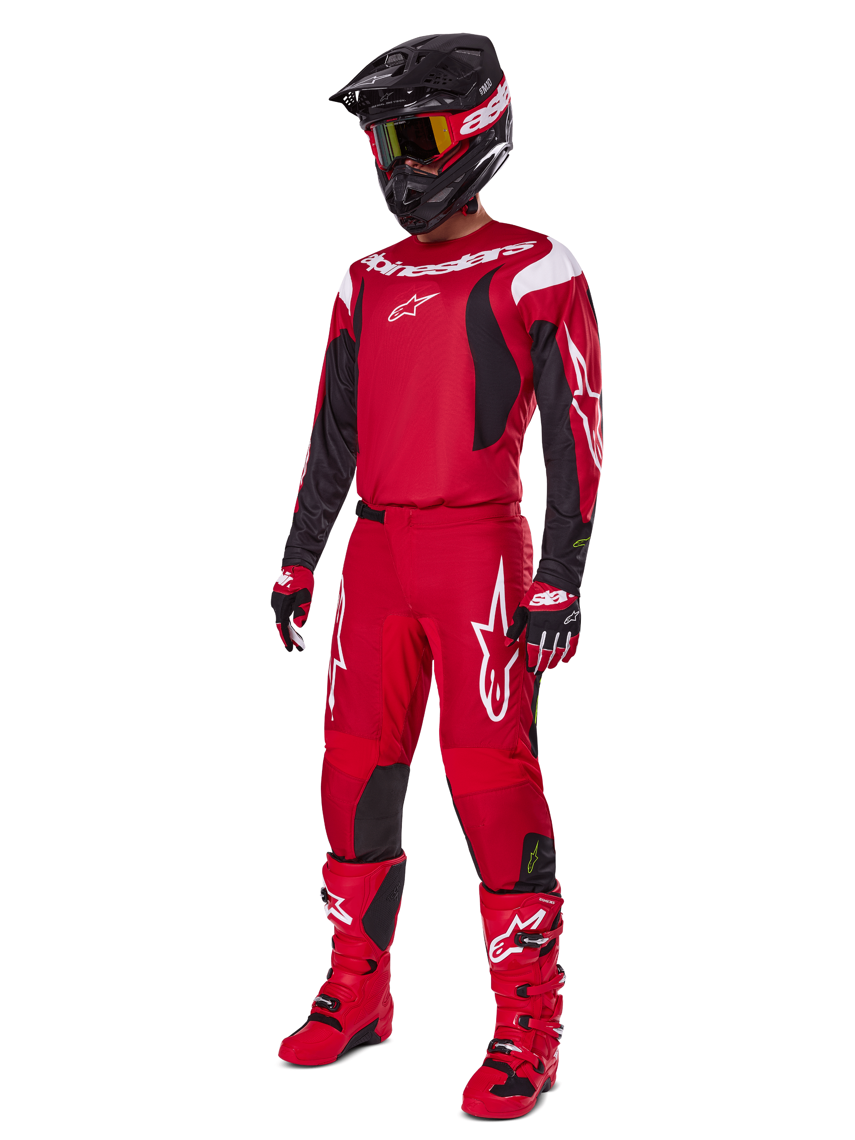 Zawodnik motocrossowy ubrany w zestaw Alpinestars Fluid Haul 2025, jasnoczerwony z czarnymi i białymi akcentami, kompletny strój zawierający koszulkę, spodnie, kask, buty i rękawice, zaprojektowany dla wydajności i ochrony off-road