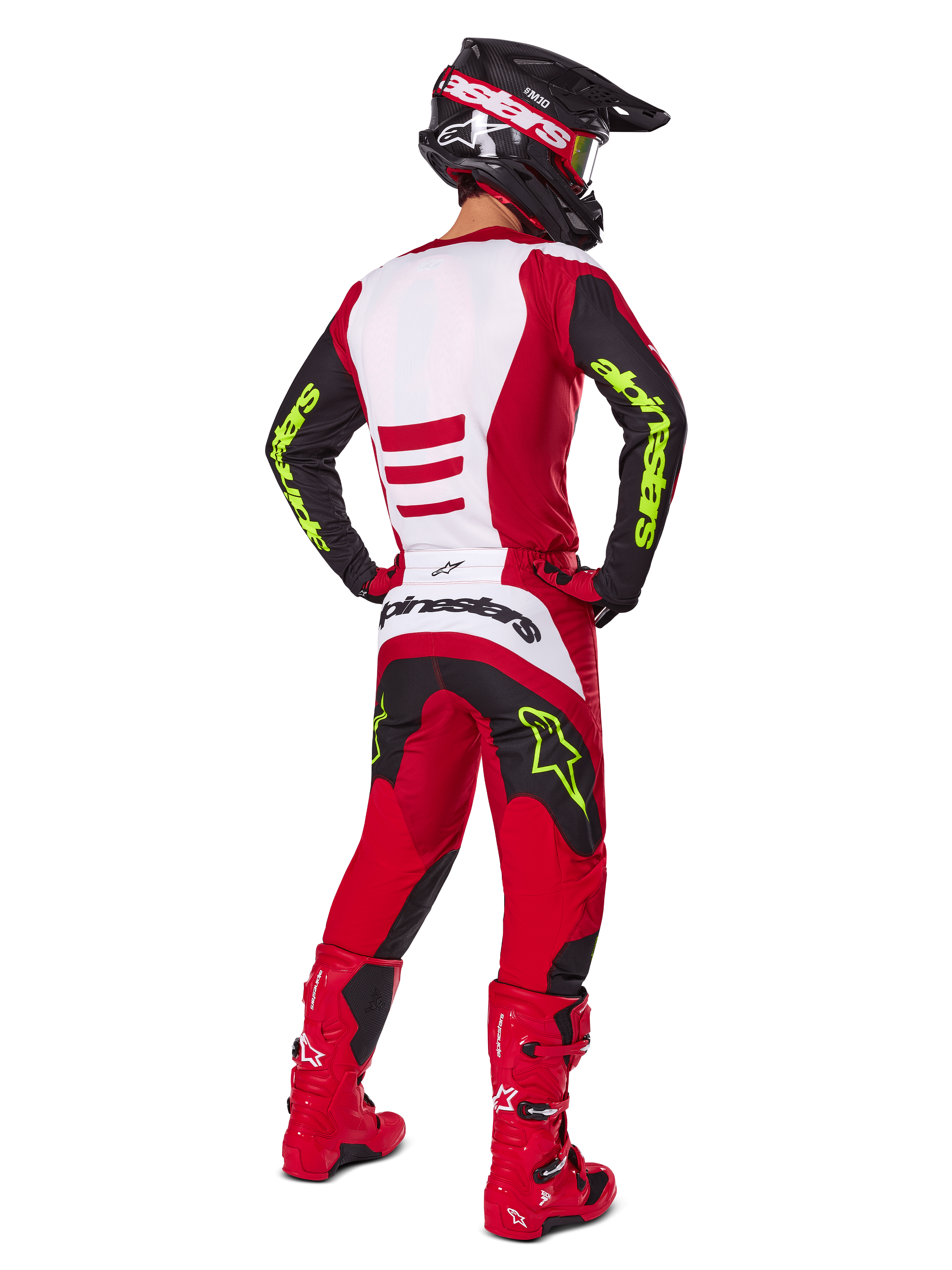 Motocyklista motocrossowy od tyłu w zestawie Alpinestars 2025 Fluid Haul, jaskrawoczerwony i czarny z białymi panelami, neonowożółte logo na rękawach i spodniach, dopasowane czerwone buty i czarny kask, kompletny profesjonalny strój do jazdy terenowej
