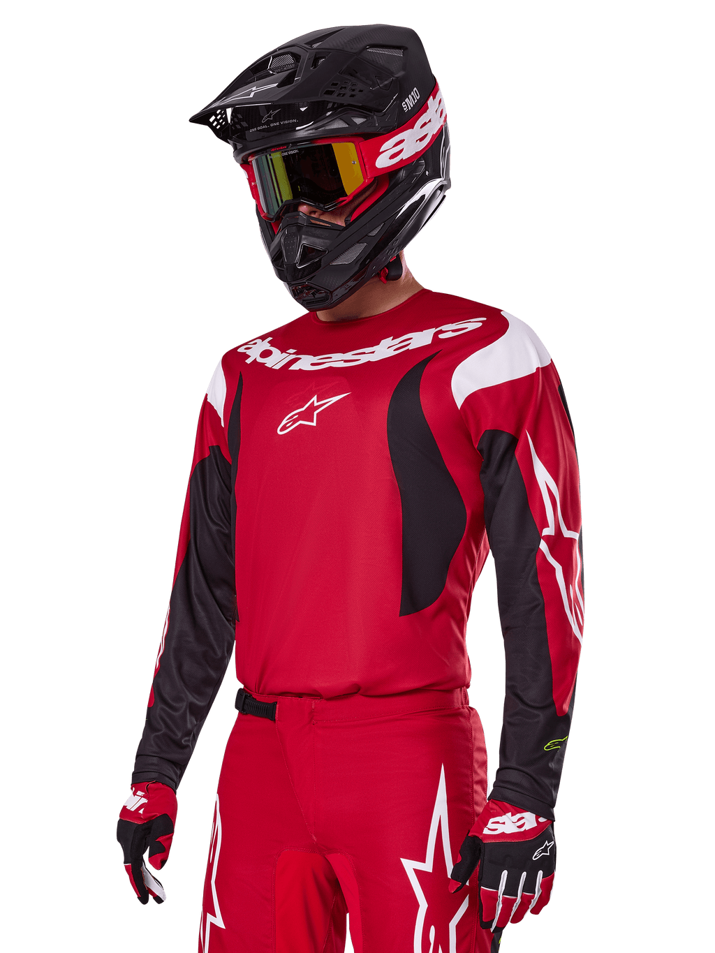 Zawodnik motocrossowy w zestawie Alpinestars 2025 Fluid Haul w kolorze czerwonym, czerwona koszulka z białymi i czarnymi akcentami, pasujące czerwone spodnie z białą grafiką, czarny kask z białym logo, czerwono-żółte gogle, czerwono-czarne rękawice, kompletny strój wyścigowy do motocrossu