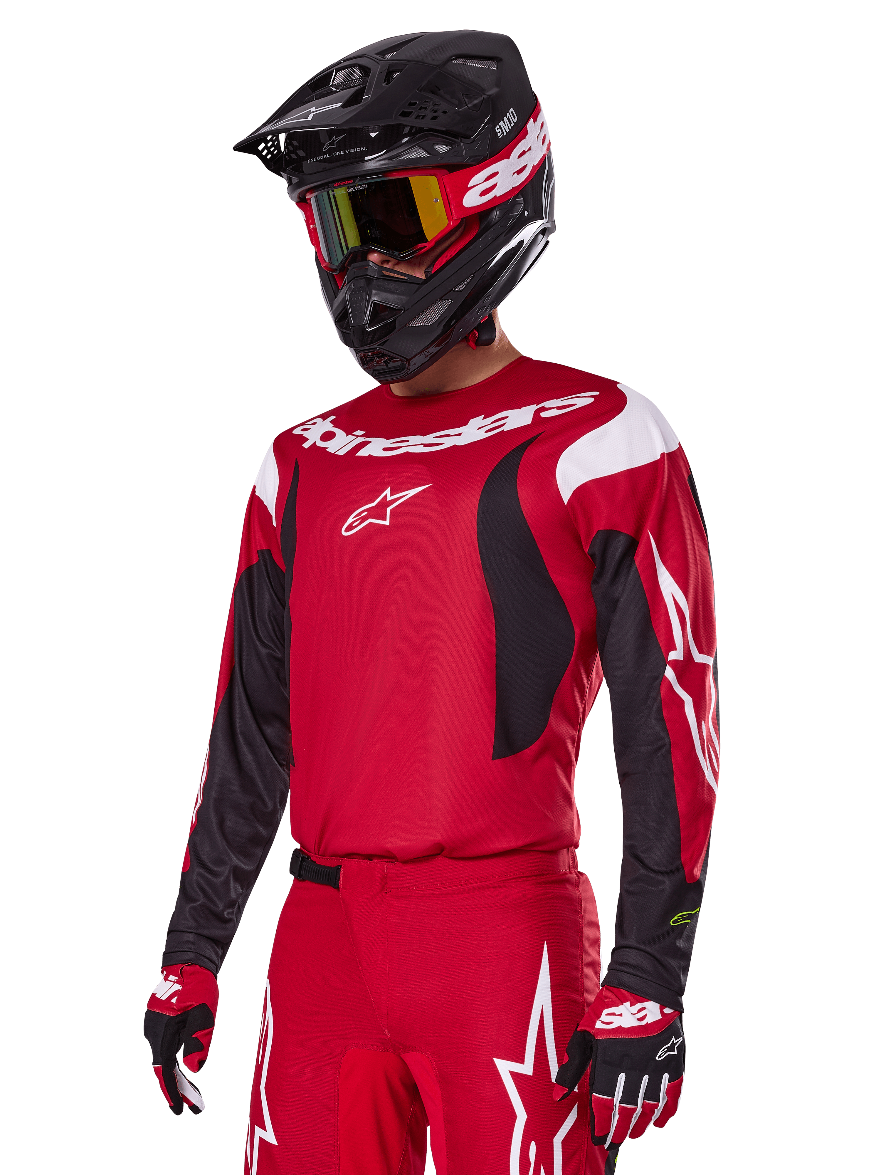 Zawodnik motocrossowy w zestawie Alpinestars 2025 Fluid Haul w kolorze czerwonym, czerwona koszulka z białymi i czarnymi akcentami, pasujące czerwone spodnie z białą grafiką, czarny kask z białym logo, czerwono-żółte gogle, czerwono-czarne rękawice, kompletny strój wyścigowy do motocrossu