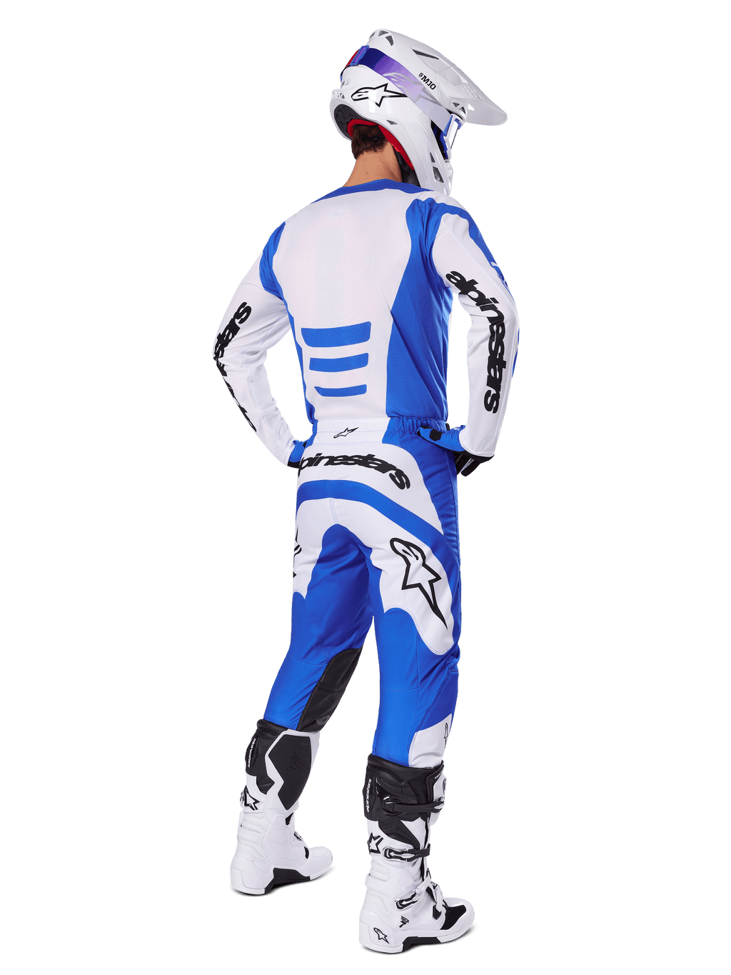 Jeździec motocrossowy widziany od tyłu w zestawie Alpinestars 2025 Fluid Haul, niebiesko-biała koszulka i pasujące spodnie, biały kask z niebieskimi akcentami oraz biało-czarne buty wyścigowe, dopasowany strój do jazdy terenowej