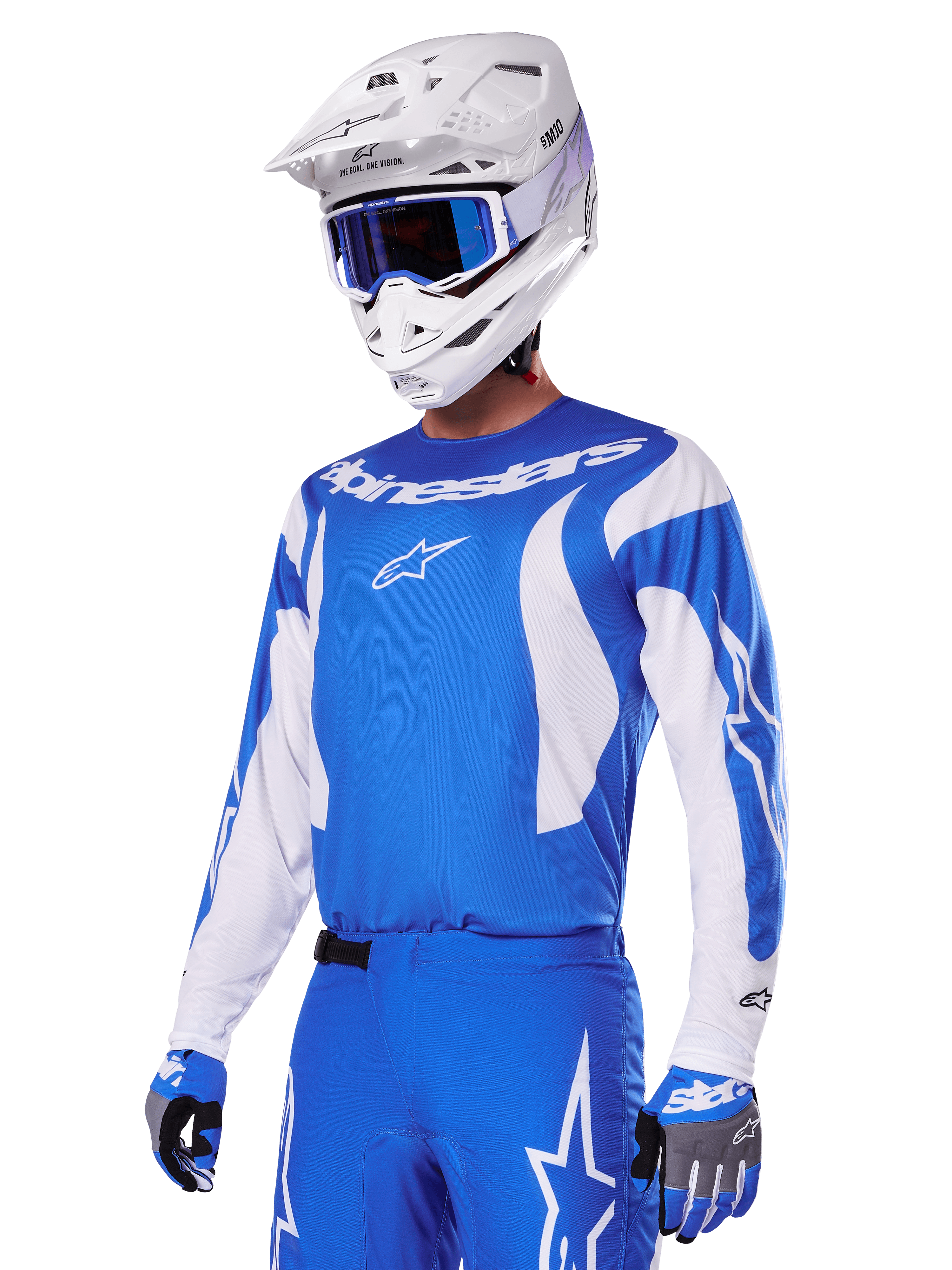 Zawodnik motocrossowy w zestawie Alpinestars 2025 Fluid Haul w kolorze niebiesko-białym, niebieska koszulka z białymi akcentami, pasujące niebieskie spodnie z logo gwiazdy, biały kask z niebieskimi goglami i dopasowane niebiesko-szare rękawice, kompletny strój wyścigowy off-road