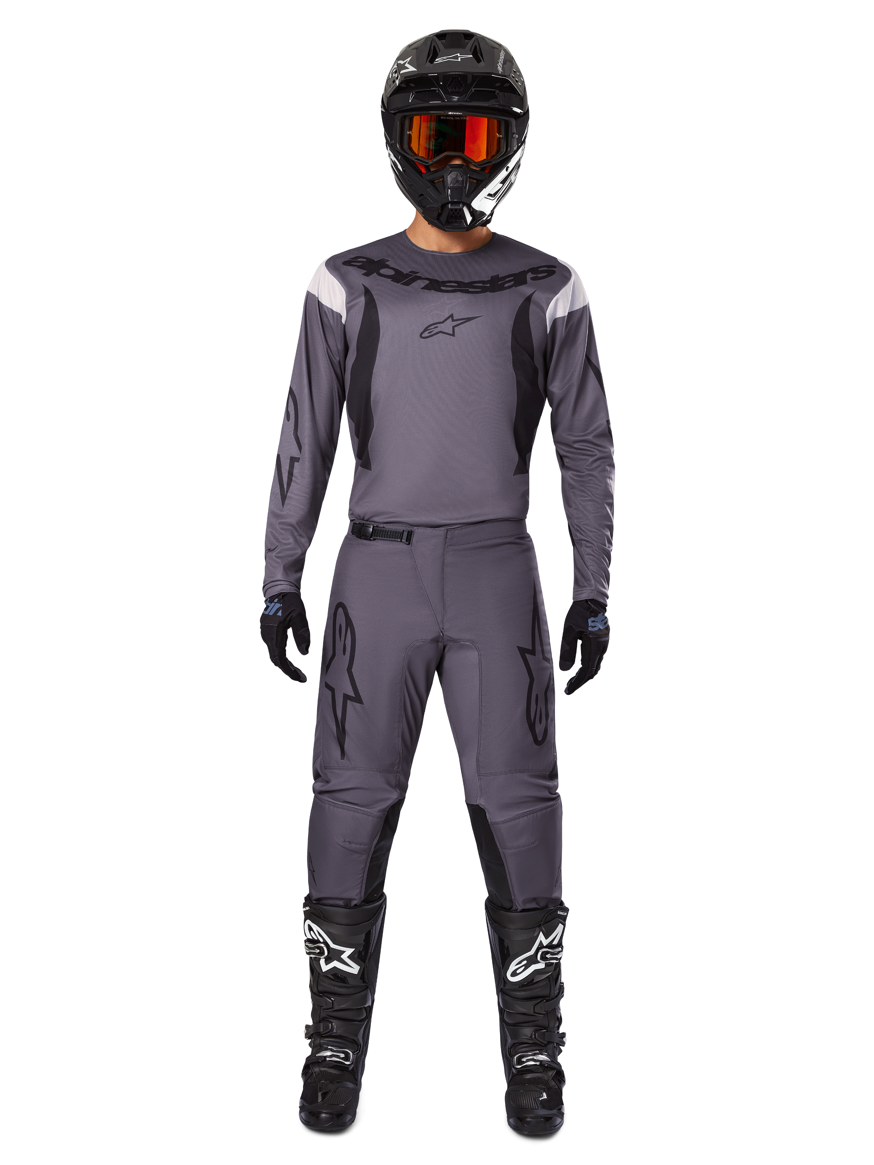 Alpinestars 2025 Fluid Haul Gear Set, odzież motocrossowa, szary, szara koszulka i spodnie z czarnymi akcentami, czarny kask z pomarańczowymi goglami, czarne buty z białym logo, skoordynowany strój wyścigowy do jazdy terenowej