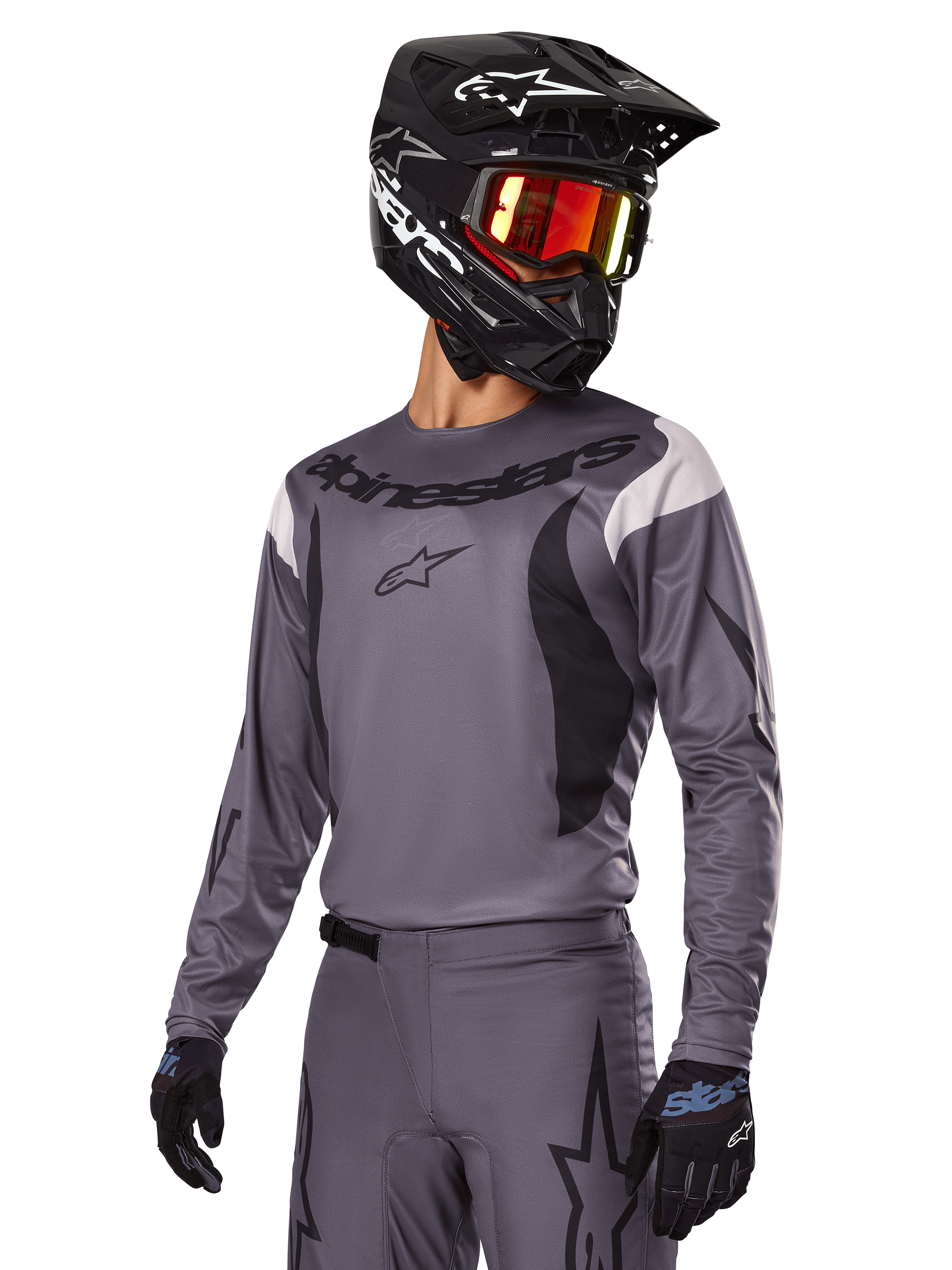 Zestaw Alpinestars 2025 Fluid Haul, szara koszulka i spodnie motocrossowe z czarnymi i białymi akcentami, noszony z czarnym kaskiem, czerwonymi goglami i czarnymi rękawicami, sportowy krój do jazdy off-road