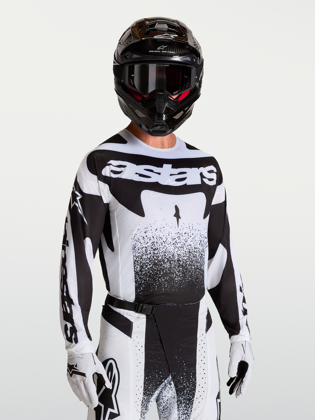 Koszulka Techstar Swan Alpinestars, męska koszulka motocrossowa, czarna i biała, sportowy krój, laserowo wycinana wentylacja, model w kasku i rękawicach.