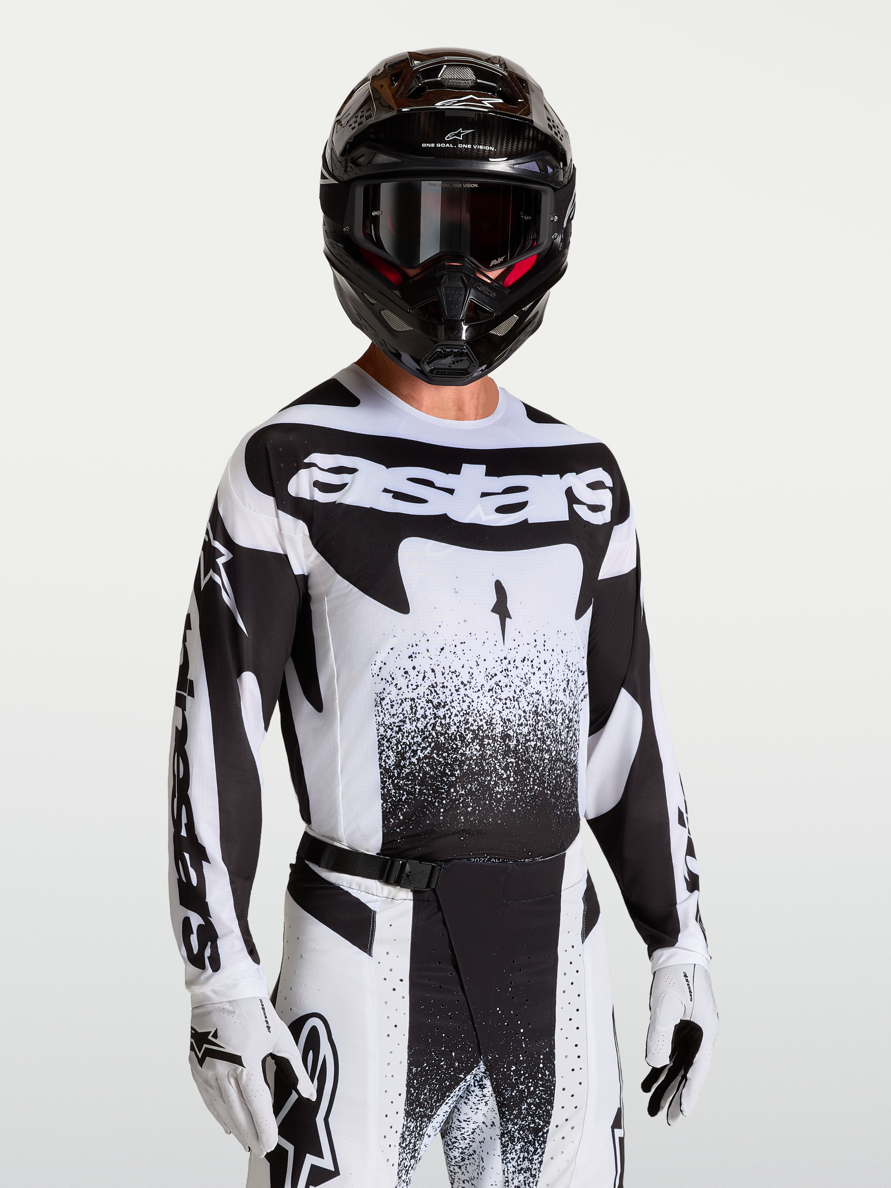 Koszulka Techstar Swan Alpinestars, męska koszulka motocrossowa, czarna i biała, sportowy krój, laserowo wycinana wentylacja, model w kasku i rękawicach.