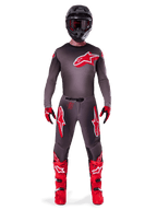 Motocross rider wearing Alpinestars 2025 Supertech Lipan Gear Set, Smoke and Bright Red, dark grey jersey and pants with bold red Alpinestars logos, bright red boots, black helmet, and red gloves, coordinated professional outfit for off-road racing