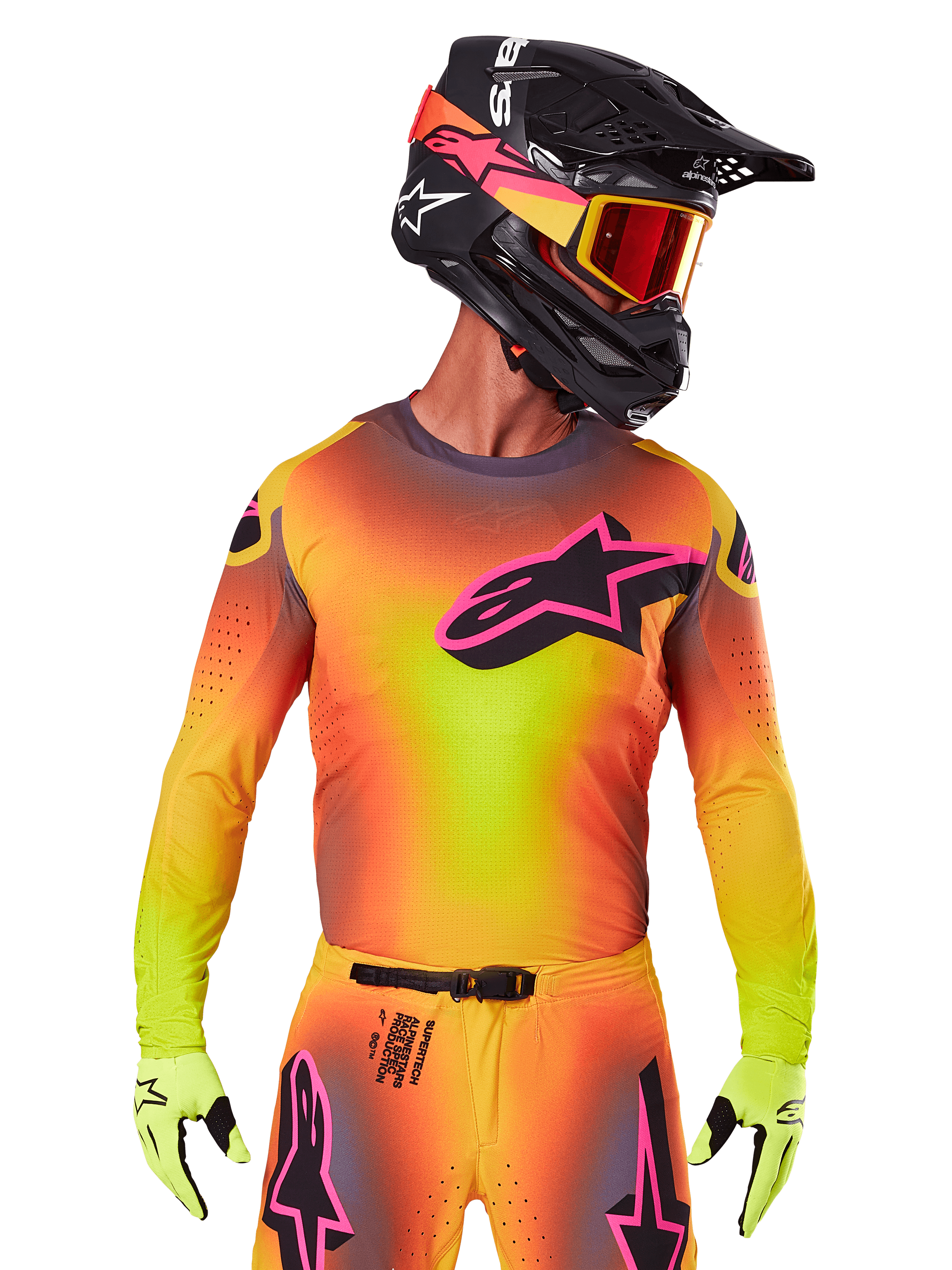 Motocyklista motocrossowy ubrany w koszulkę 2025 Supertech Lipan, jaskrawy gradient kolorów żółtego, pomarańczowego i różowego, duże czarne logo gwiazdy Alpinestars z różową obwódką na piersi, laserowo wycinane perforacje dla wentylacji, sportowy krój wyścigowy, w zestawie z pasującymi spodniami, żółtymi rękawicami i czarnym kaskiem z goglami.
