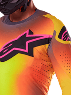 Alpinestars 2025 Supertech Lipan Jersey, zbliżenie na koszulkę motocrossową, kolor żółto-różowy z jaskrawym gradientem, duże czarne logo gwiazdy z różową obwódką na piersi, widoczne laserowo wycinane perforacje dla lepszej wentylacji