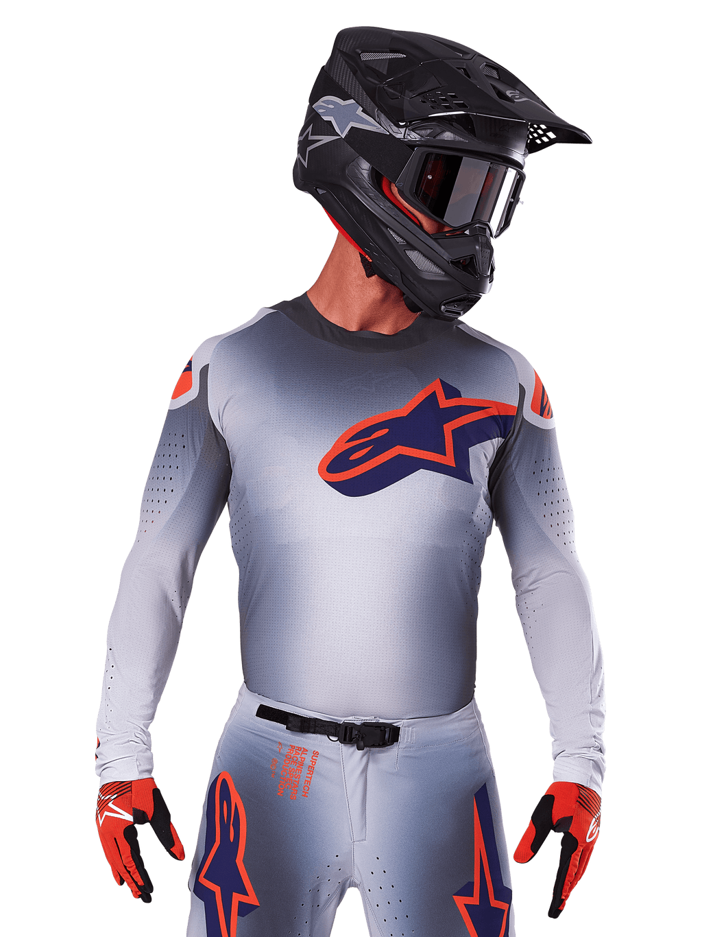 Alpinestars Supertech Lipan Jersey 2025, koszulka motocrossowa, szara z pomarańczowymi i granatowymi akcentami, techniczna koszulka z długim rękawem i perforowanymi detalami wentylacyjnymi, noszona z czarnym kaskiem i czerwonymi rękawicami, nowoczesny design wyścigowy