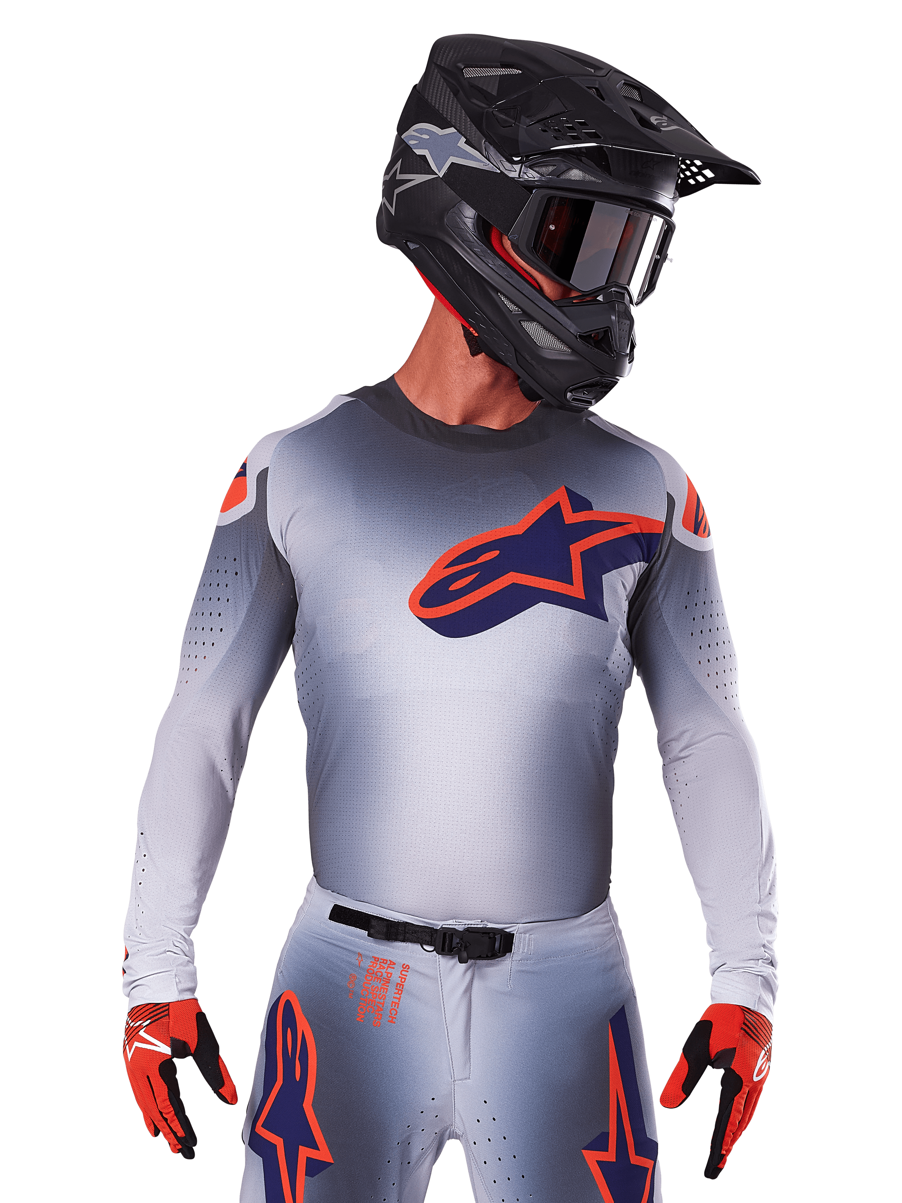 Alpinestars Supertech Lipan Jersey 2025, koszulka motocrossowa, szara z pomarańczowymi i granatowymi akcentami, techniczna koszulka z długim rękawem i perforowanymi detalami wentylacyjnymi, noszona z czarnym kaskiem i czerwonymi rękawicami, nowoczesny design wyścigowy