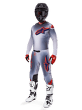 Zestaw motocrossowy Alpinestars Supertech Lipan 2025, szary z grafikami gwiazd w kolorach pomarańczowym fluo i granatowym, czarny kask, czerwono-czarne rękawice i biało-czarne buty, kompletny profesjonalny strój terenowy o wentylowanej konstrukcji