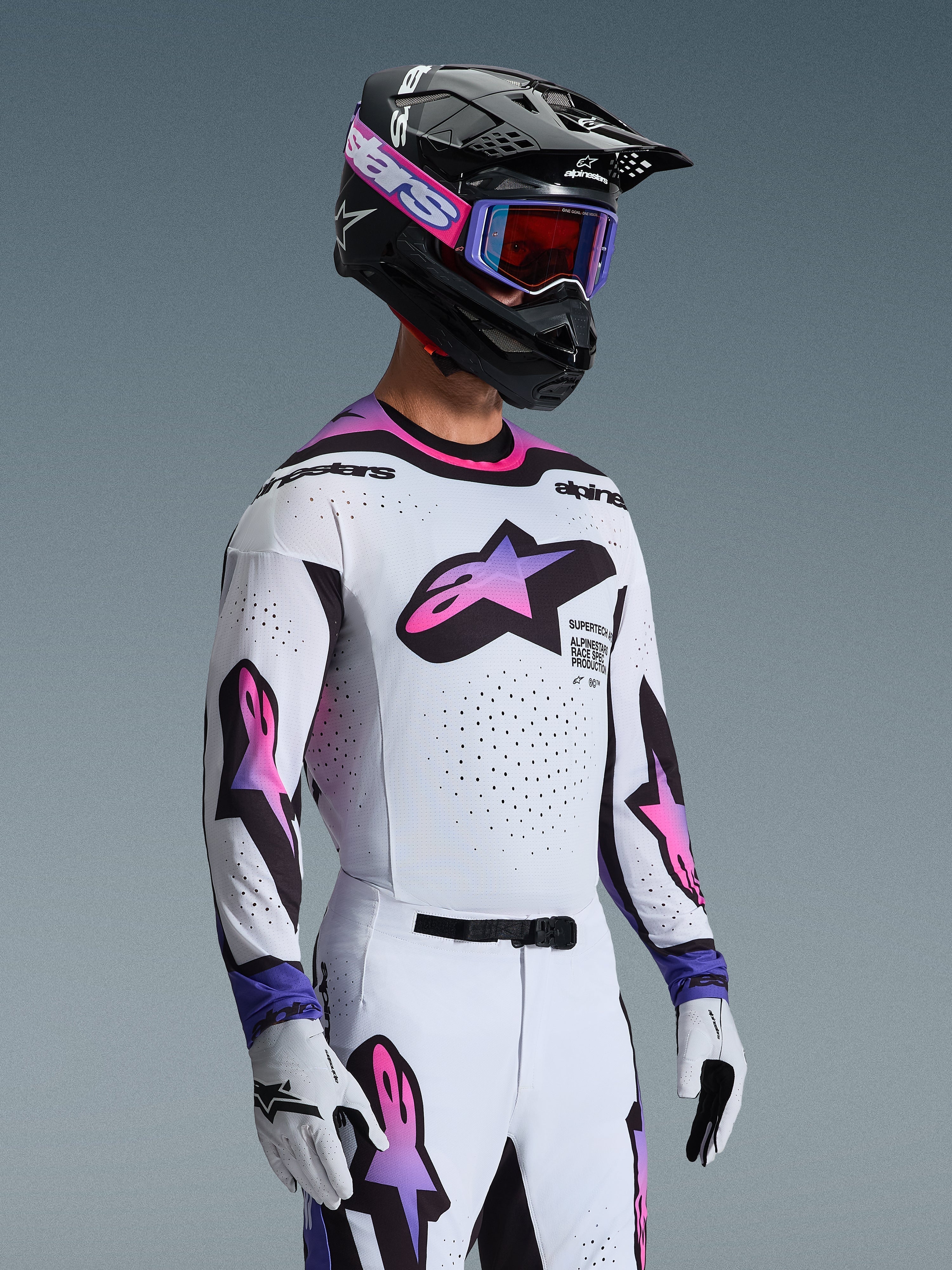 Zawodnik motocrossowy ubrany w koszulkę 2026 Supertech AFD Vista w kolorze White Purple Black, pasujące biało-fioletowe spodnie, czarny kask z fioletowymi goglami i białe rękawice, kompletny profesjonalny strój do wyścigów terenowych