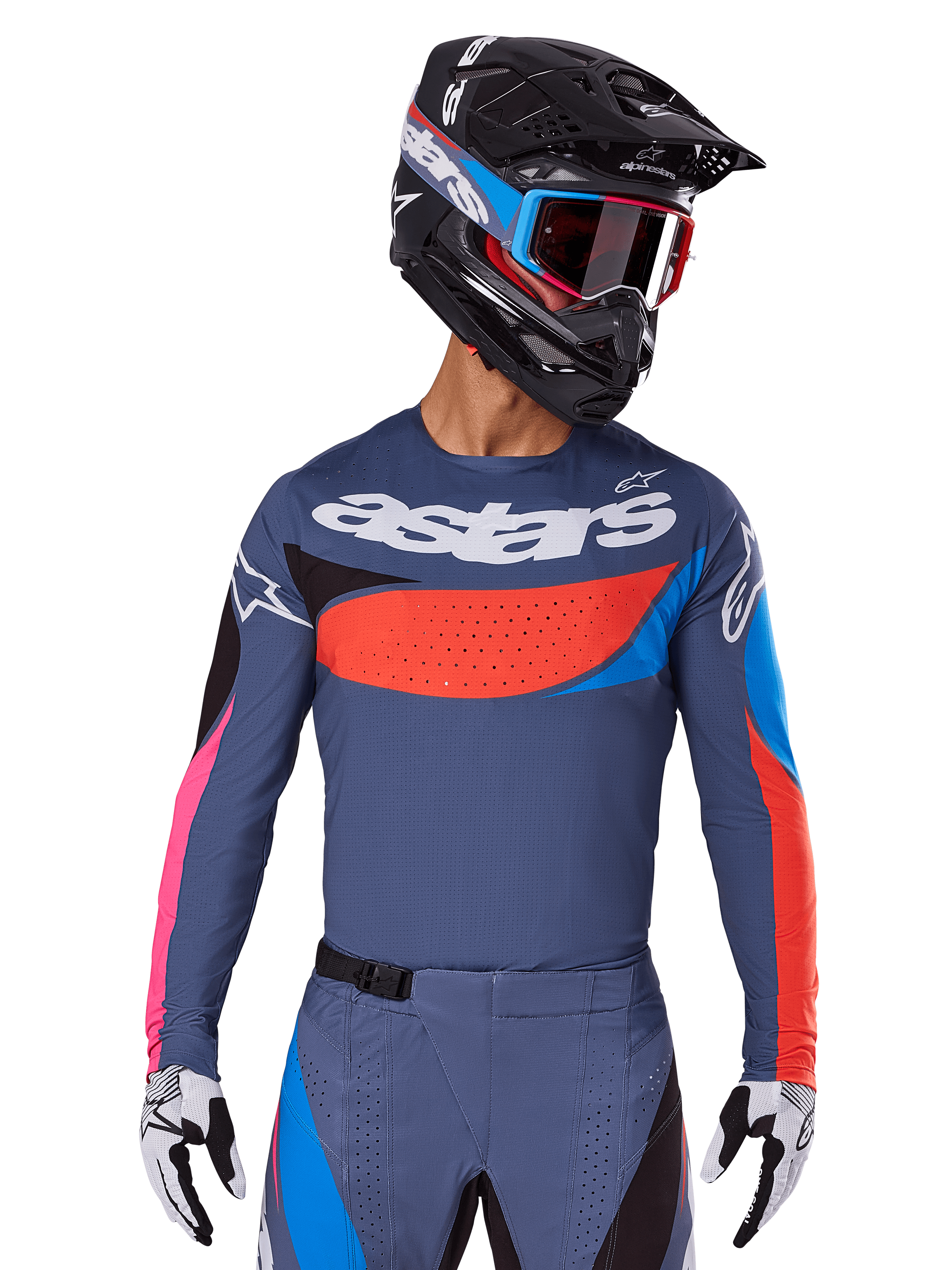 Alpinestars 2025 Techstar Dreem Jersey, koszulka motocrossowa, szara z niebieskimi, czerwonymi i różowymi akcentami, z laserowo wycinanymi perforacjami i dużym logo na klatce piersiowej, noszona z pasującymi spodniami i czarnym kaskiem wyścigowym