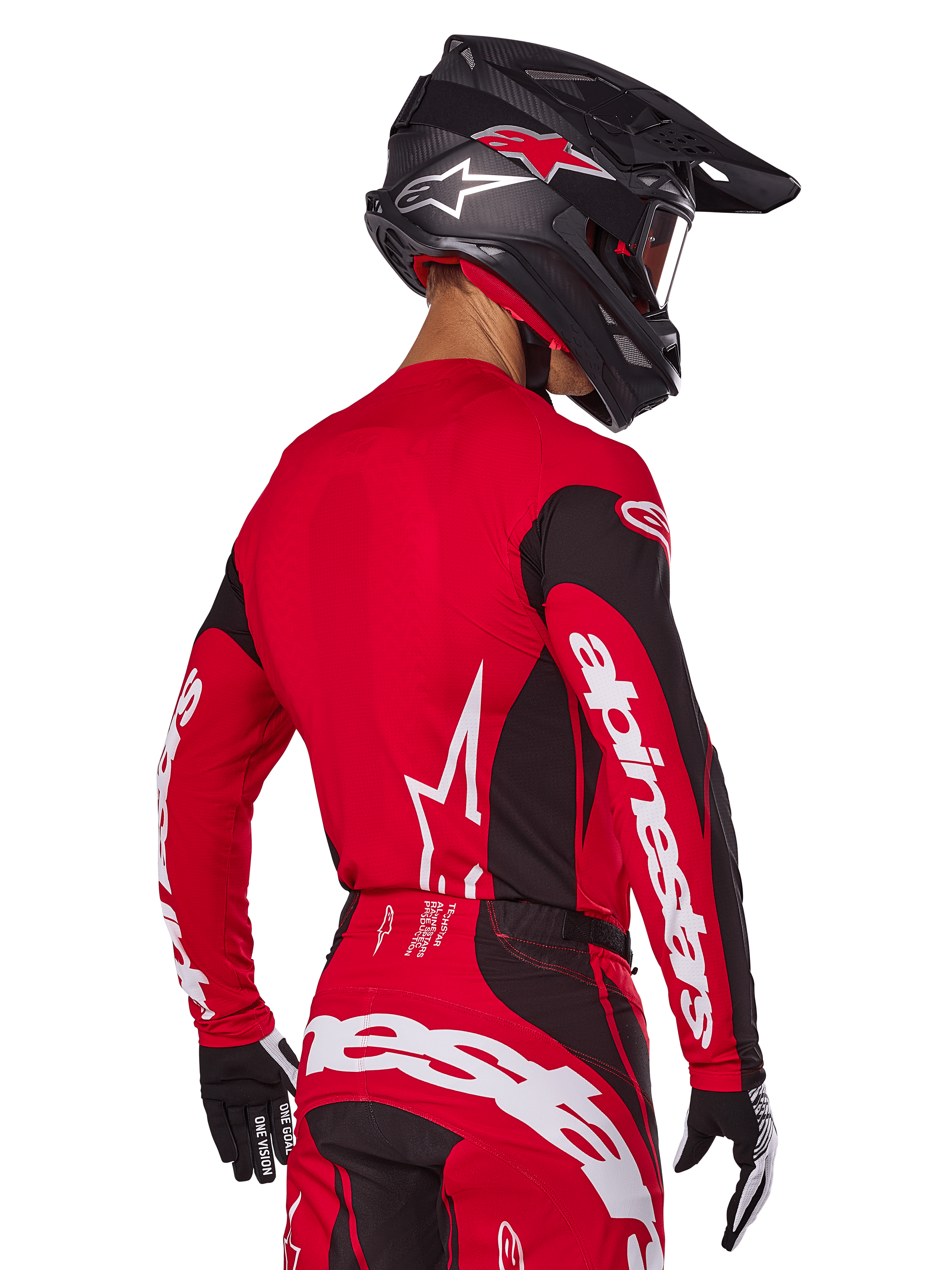 Zawodnik motocrossowy widziany z tyłu w zestawie Alpinestars 2025 Techstar Dreem, czerwono-czarna koszulka z białym brandingiem na rękawach, pasujące czerwono-czarne spodnie z wyraźnym białym logo na siedzeniu, czarny karbonowy kask z czerwonymi akcentami, czarno-białe rękawice, profesjonalny strój do wyścigów terenowych