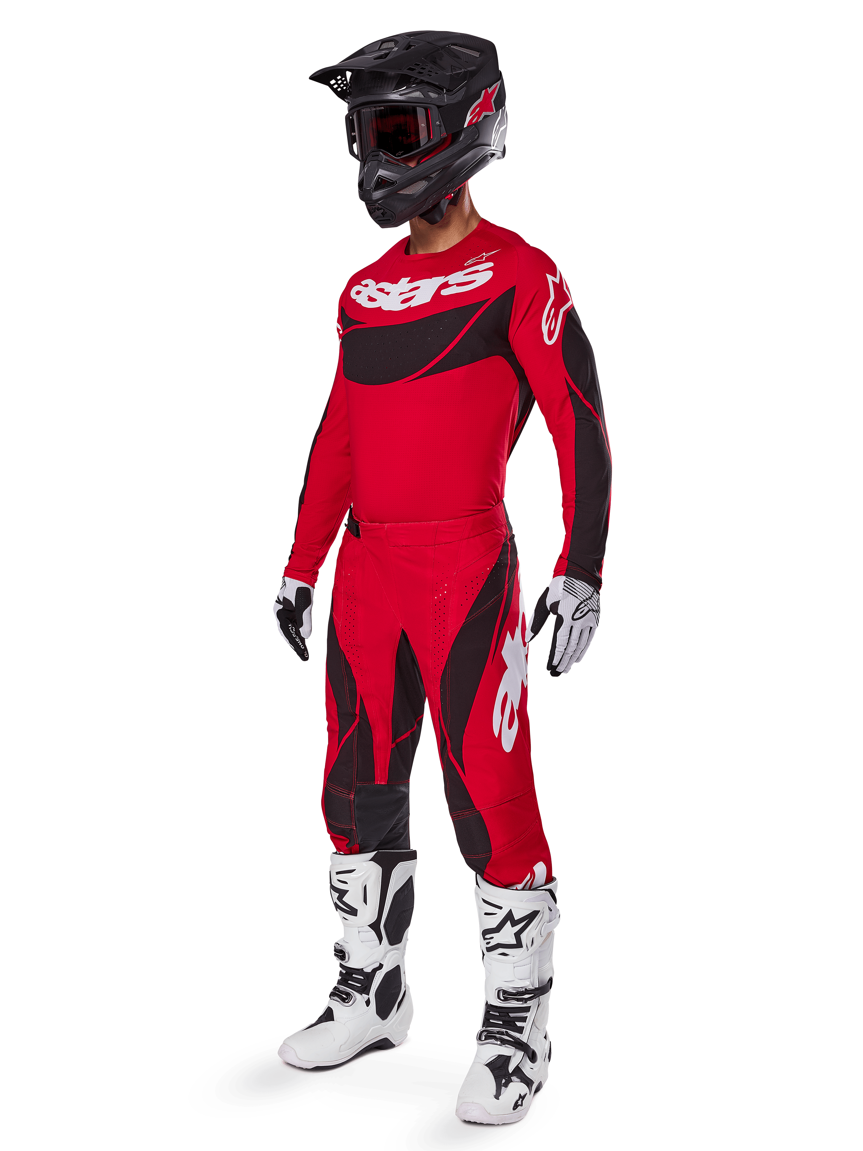 Widok całej sylwetki zawodnika motocrossowego w zestawie odzieży 2025 Techstar Dreem w kolorze jaskrawoczerwonym i czarnym, z koszulką wydajnościową z białym brandingiem, pasującymi elastycznymi spodniami ripstop, czarnym kaskiem z czerwonym daszkiem, biało-czarnymi rękawicami i białymi butami Tech, specjalistyczny strój wyścigowy do zawodów off-road.
