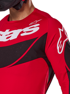 Alpinestars 2025 Techstar Dreem Jersey, koszulka motocrossowa, jaskrawoczerwona i czarna, zbliżenie na klatkę piersiową i ramię z białym logo, czarne ukośne panele z laserowo wycinanymi perforacjami zapewniającymi wentylację, sportowy krój wyścigowy zapewniający wydajność w terenie