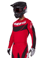 Zestaw Alpinestars 2025 Techstar Dreem, czerwona koszulka i spodnie motocrossowe z czarnymi i białymi akcentami, czarny kask i gogle, biało-czarne rękawice, z wyraźnym brandingiem „astars”, zaprojektowany do wyczynowej jazdy terenowej