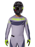 Alpinestars Techstar Dreem Jersey i zestaw odzieży 2025, strój motocrossowy, jasnoszary i ciemnoszary z neonowożółtymi akcentami, z logo „astars”, noszony z czarnym kaskiem, goglami i dopasowanymi rękawicami, techniczny perforowany materiał zapewniający wydajność w terenie