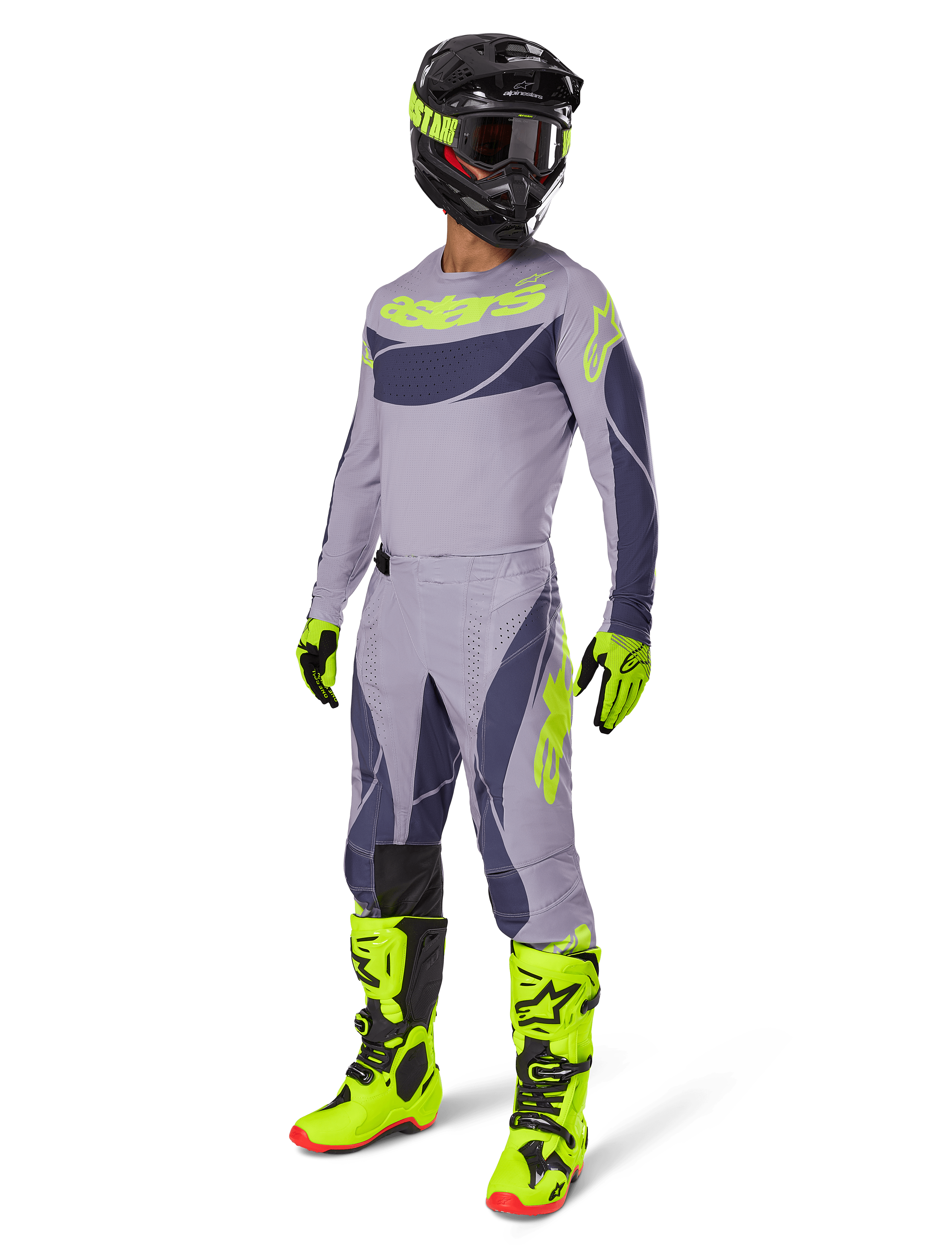 Zestaw Alpinestars 2025 Techstar Dreem, zawodnik motocrossowy w pełnym stroju wyścigowym, szara koszulka i spodnie z ciemnoszarymi wzorami i neonowymi żółto-zielonymi akcentami, dopasowany czarny kask, neonowe żółto-zielone rękawice i buty, wyczynowa odzież off-road