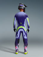Motocrossowiec widoczny od tyłu w koszulce Alpinestars 2026 Supertech Scenz w kolorze Purple Yellow Fluo, z fioletowym gradientem i żółtymi detalami marki, w komplecie z dopasowanymi spodniami motocrossowymi i fioletowymi butami, pełny zestaw wyścigowy off-road