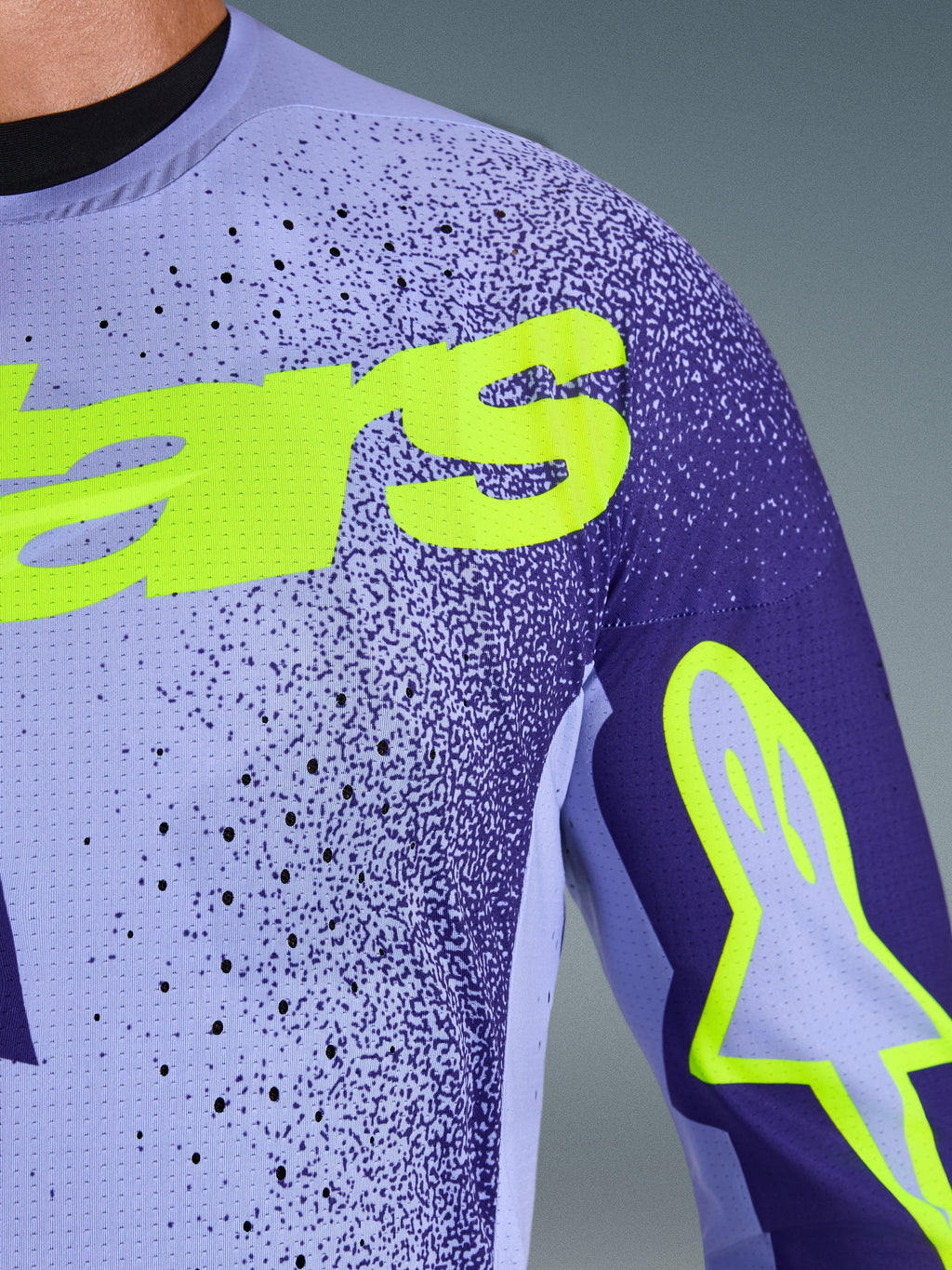 Alpinestars 2026 Supertech Scenz Jersey, koszulka motocrossowa, fioletowa i żółta neonowa, zbliżenie na perforowany, elastyczny materiał siatkowy oraz jaskrawożółte logo Alpinestars na klatce piersiowej i rękawie