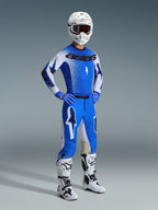 Zawodnik motocrossowy w zestawie Alpinestars 2026 Supertech Scenz w kolorze niebieskim (Ucla Blue) i białym, profesjonalna koszulka z brandingiem „astars”, pasujące spodnie wyczynowe, biały kask, ciemne gogle oraz biało-czarne buty terenowe