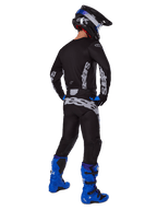 Motocrossista widziany z tyłu w zestawie Alpinestars 2025 Racer Graphite, czarno-szara koszulka i spodnie z szarym brandingiem, jasnoniebieskie buty motocrossowe, czarno-niebieski kask oraz niebieskie rękawice, kompletny strój off-road