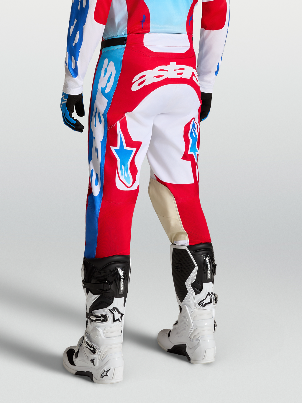 Alpinestars Spodnie Racer Hunt, męskie spodnie motocrossowe, czerwone i białe, grafiki z gwiazdami, panele kolanowe ze skóry koziej, widok z tyłu na modelu