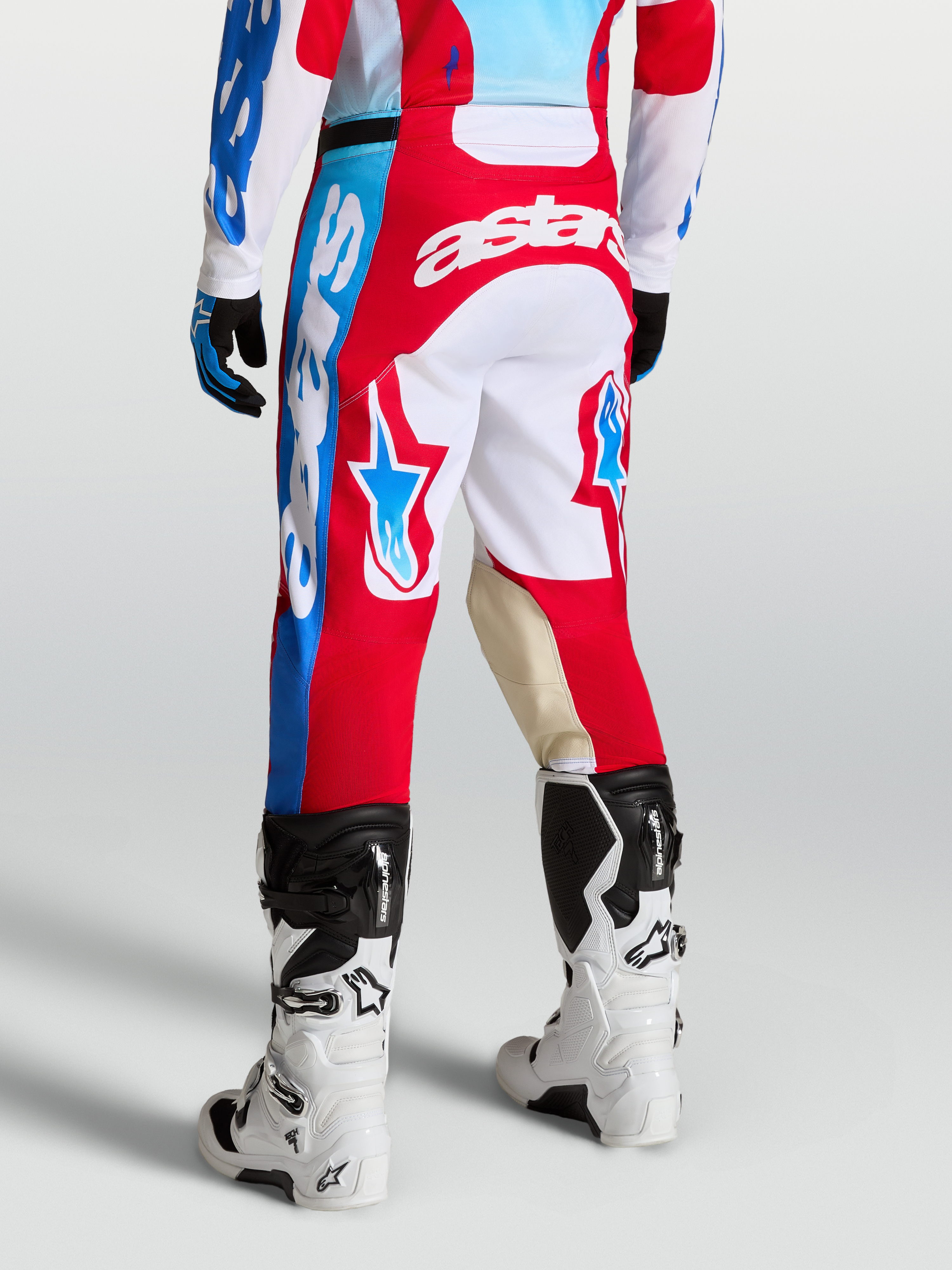 Alpinestars Spodnie Racer Hunt, męskie spodnie motocrossowe, czerwone i białe, grafiki z gwiazdami, panele kolanowe ze skóry koziej, widok z tyłu na modelu
