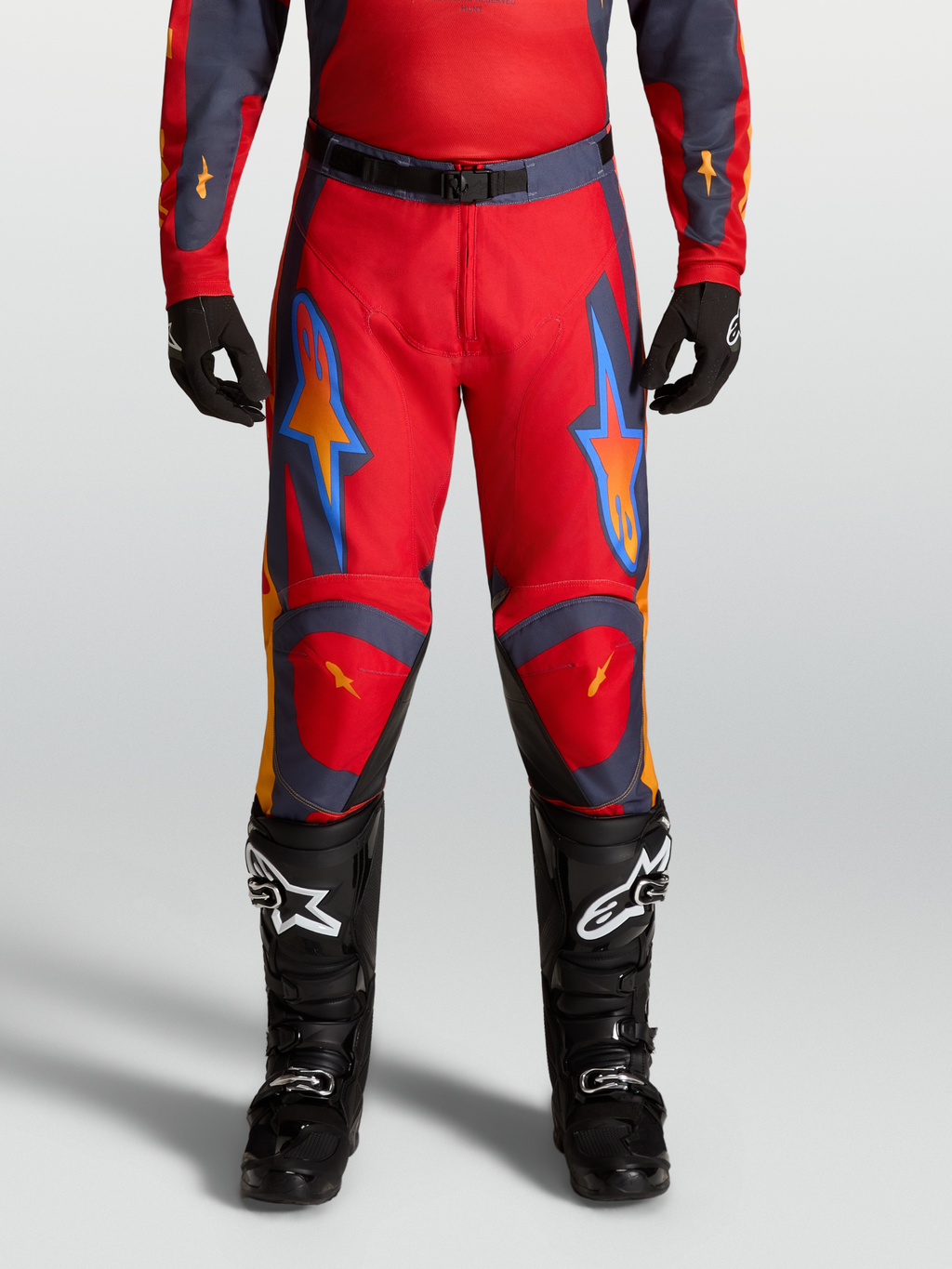 Alpinestars spodnie Racer Hunt 2027, czerwone i szare męskie spodnie motocrossowe o wstępnie zakrzywionym kroju.