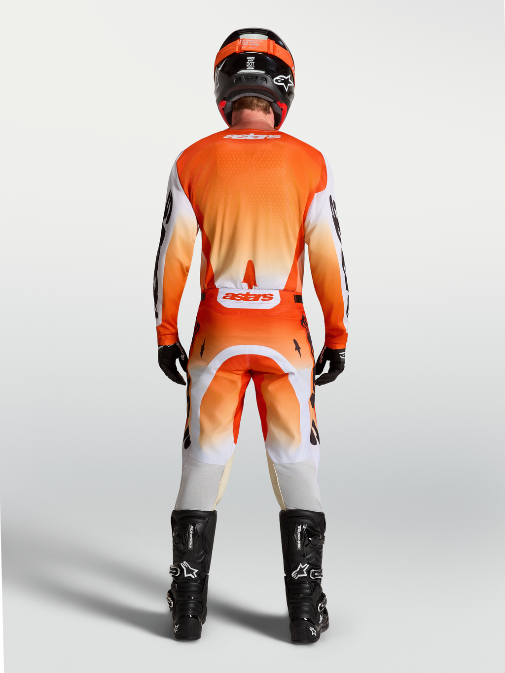Koszulka Alpinestars Racer Amber, pomarańczowa i biała, widok z tyłu na modelu, oddychający krój wyścigowy do motocrossu.