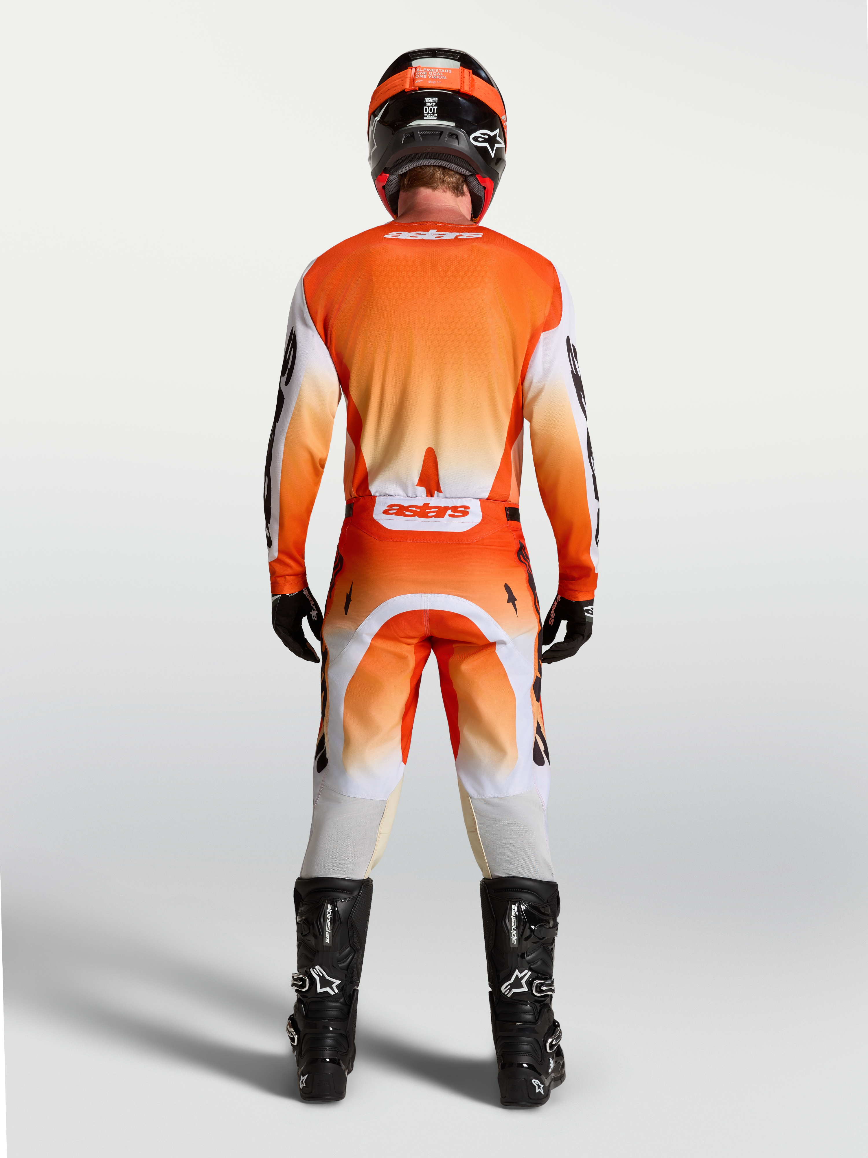 Koszulka Alpinestars Racer Amber, pomarańczowa i biała, widok z tyłu na modelu, oddychający krój wyścigowy do motocrossu.