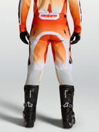 Alpinestars Spodnie Racer Amber, męskie spodnie motocrossowe, czerwone i białe, widok od tyłu na modelu z czarnymi butami.