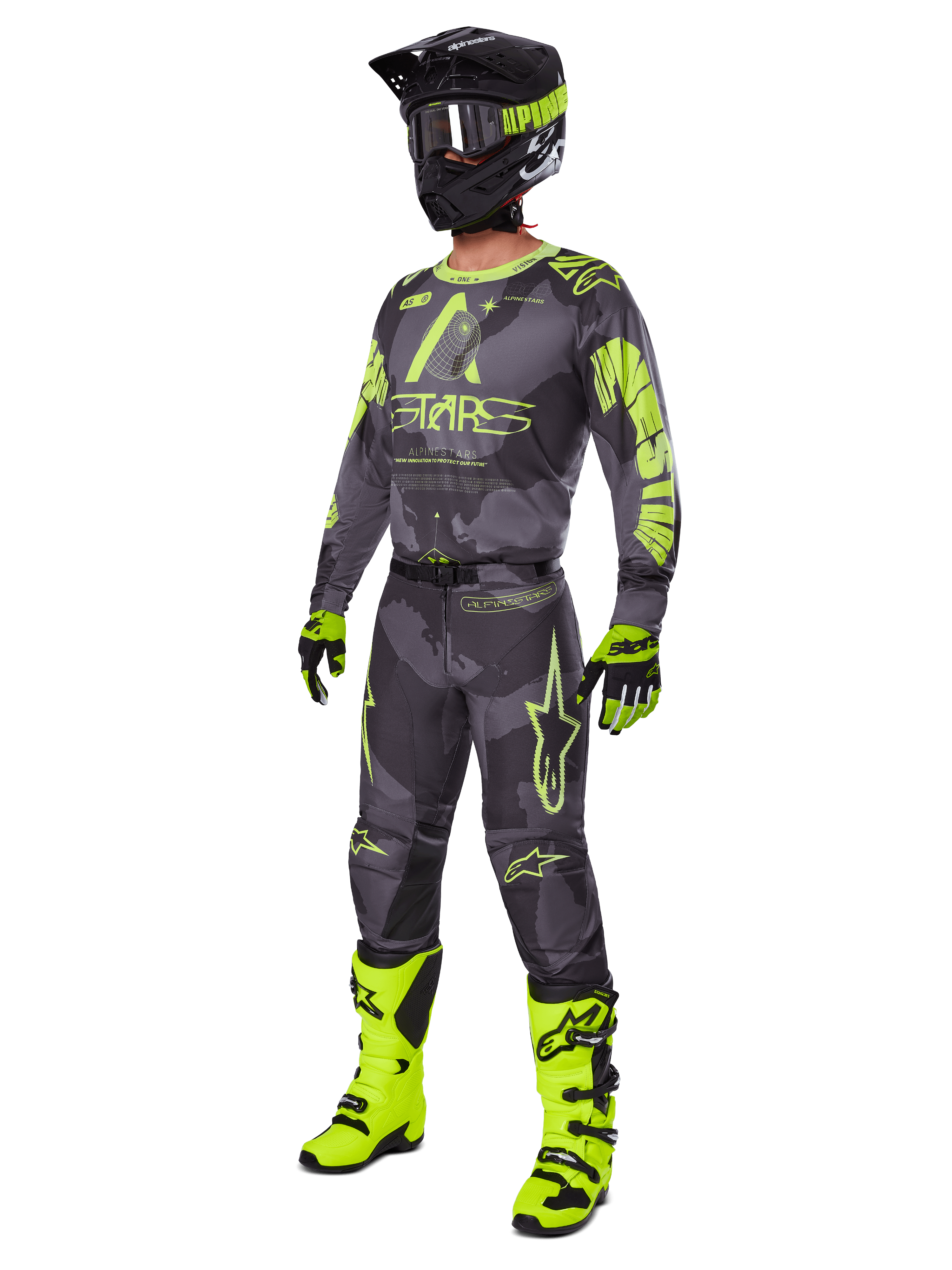 Zawodnik motocrossowy w zestawie Alpinestars 2025 Racer Hollow, koszulka i spodnie w kolorach Dark Camo i Yellow Fluo, czarno-żółty neonowy kask, pasujące rękawice i jaskrawożółte neonowe buty, kompletny strój do wyścigów terenowych