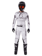 Alpinestars 2025 Racer Hollow Gear Set, biały z czarnymi i szarymi grafikami, kompletny strój motocrossowy z koszulką i spodniami, czarny kask, pomarańczowe gogle, czarne rękawice i czarne buty, wysokiej klasy odzież terenowa