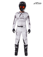 Alpinestars Zestaw Racer Hollow 2025, męska koszulka i spodnie motocrossowe w kolorze jasnego kamuflażu brązowego i białego, przedni widok w studiu na model ubranego w pasujący kask, rękawice i buty, lekka odzież off-road o wysokich osiągach