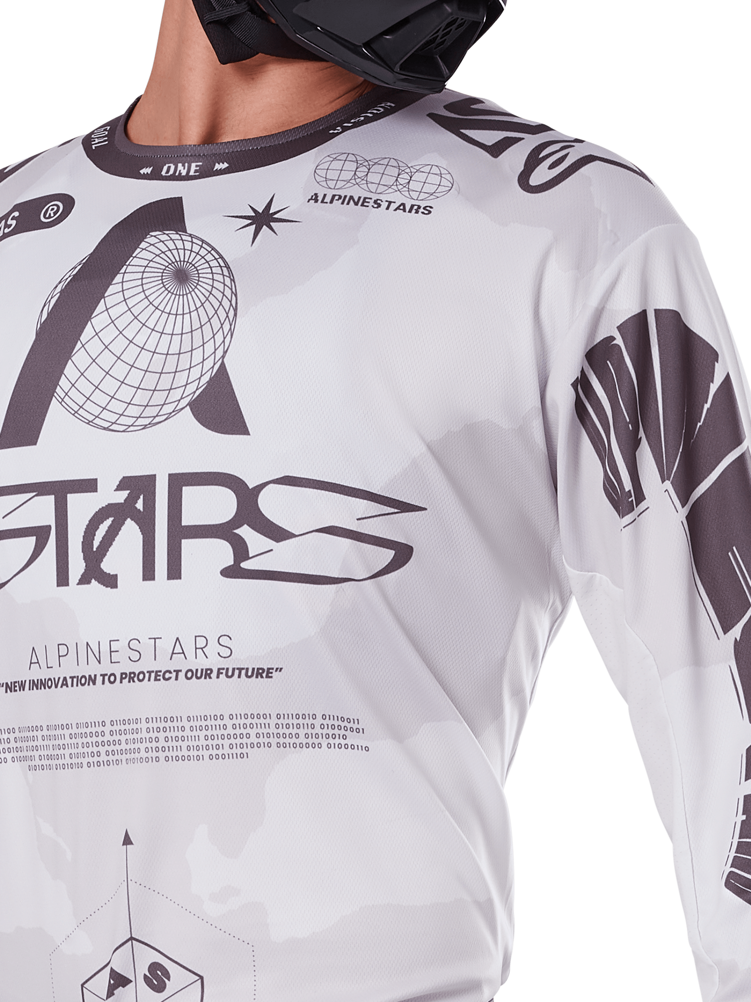 Zbliżenie na koszulkę Alpinestars 2025 Racer Hollow, biało-szara z czarnymi nadrukami graficznymi, logo globu i kodem binarnym, techniczna odzież motocrossowa do jazdy terenowej