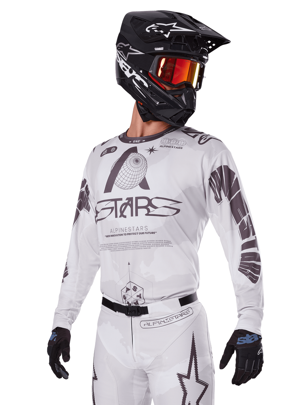 Zestaw Alpinestars 2025 Racer Hollow, koszulka i spodnie motocrossowe, białe z czarnymi i szarymi grafikami, z brandingiem „ASTARS” i motywami ażurowego globu, w połączeniu z czarnym kaskiem, czerwonymi lustrzanymi goglami i czarnymi rękawicami, zaprojektowany do wyczynowej jazdy off-road