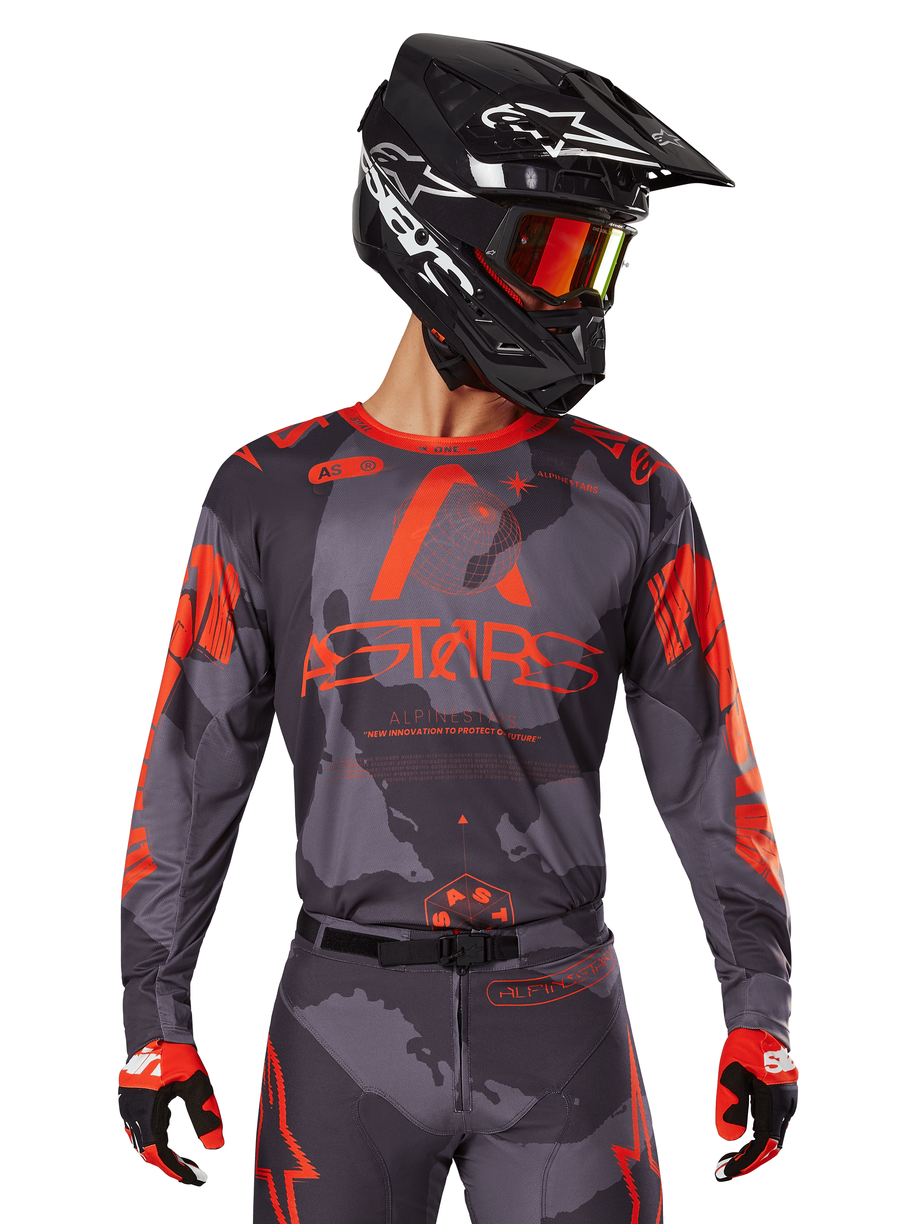 Alpinestars 2025 Racer Hollow Jersey, koszulka motocrossowa, szary kamuflaż i jaskrawy pomarańczowy, zestaw z pasującymi spodniami i rękawicami, czarny kask z białymi grafikami i goglami, wyraziste logo ASTARS, ochronna odzież do wyścigów terenowych
