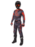Alpinestars 2025 Racer Hollow Gear Set, kompletny strój motocrossowy, szary kamuflaż i pomarańczowy fluo, zawiera czarny kask z goglami o czerwonym odcieniu, koszulkę i spodnie moro z wyrazistymi pomarańczowymi grafikami, czerwono-czarne rękawice oraz czarne buty z białym logo, ochronne wyposażenie terenowe