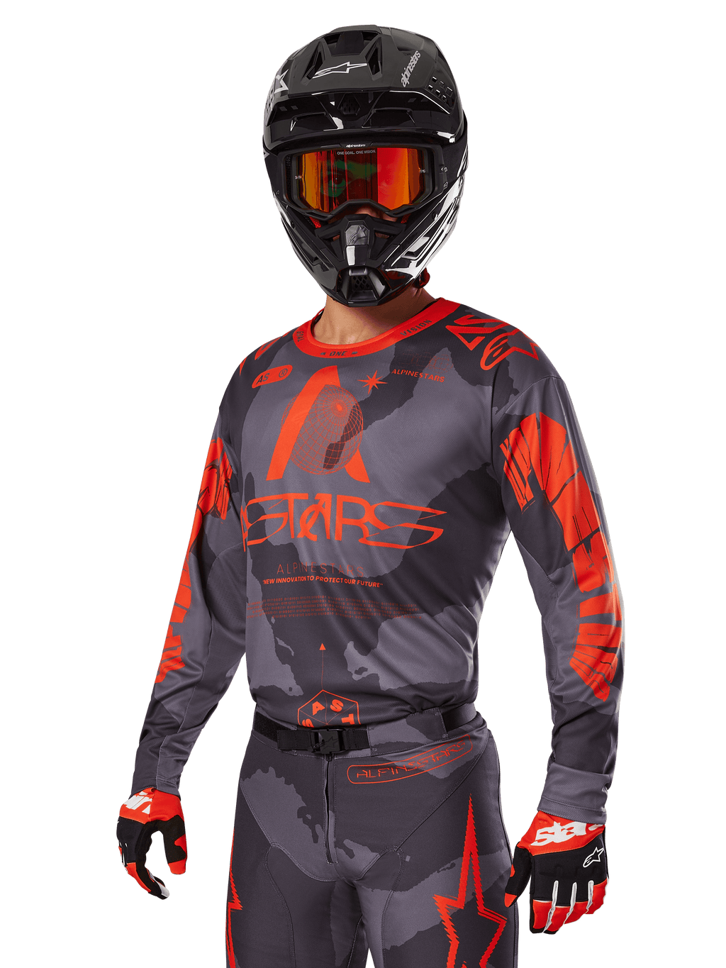 Zawodnik motocrossowy w zestawie Alpinestars 2025 Racer Hollow Red, szaro-czarny wzór kamuflażu z wyrazistym czerwonym brandingiem, komplet z koszulką, spodniami, rękawicami oraz czarnym kaskiem z czerwonymi goglami.