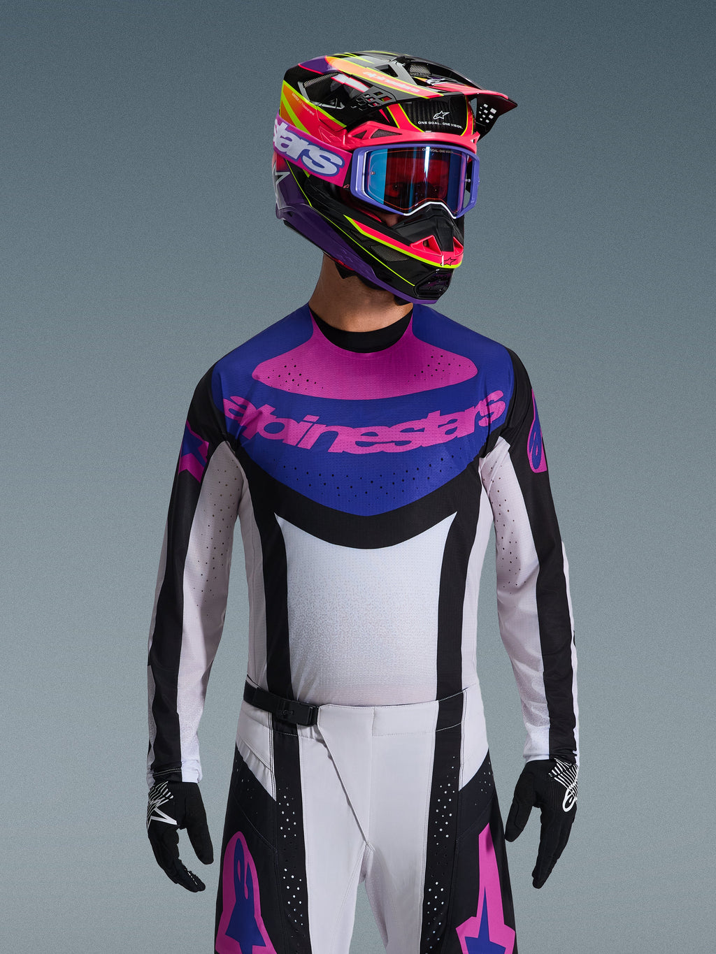 Alpinestars 2026 Techstar Knif Jersey, koszulka motocrossowa, czarna, jasnoszara i fioletowa, różowe logo Alpinestars na klatce piersiowej, noszona z pasującym kolorowym kaskiem i spodniami motocrossowymi, sportowy krój wyścigowy z laserowo wycinanymi perforacjami dla wentylacji